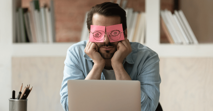 An employee with sticky notes over the eyes on the computer